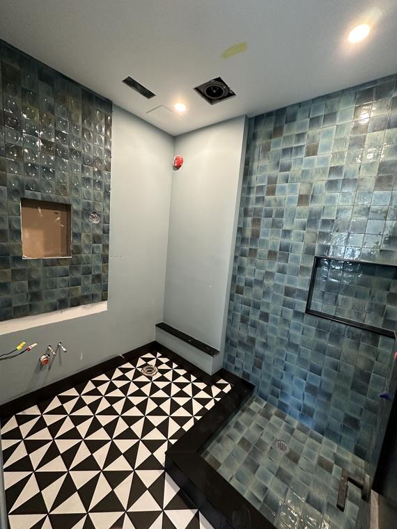 Shower with glossy blue zellige-style wall tile, a recessed niche and a patterned floor