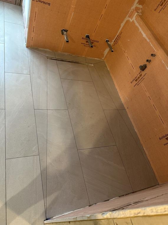 Shower walls boarded and prepared before tiling, next to a large-format tile floor