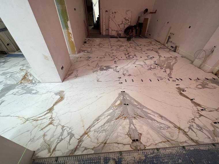 Large-format marble-look porcelain floor being installed with a levelling system