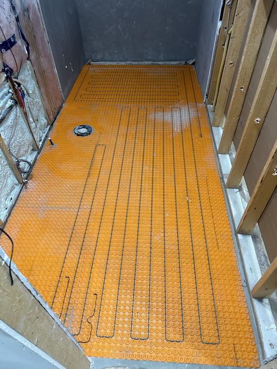 Bathroom floor prepared with an uncoupling membrane and heating cables before tiling