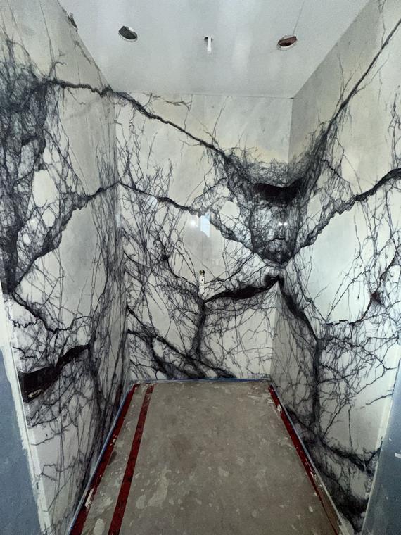 Shower clad in white slabs with dramatic black veining